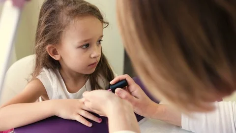 Nail master doing manicure for pretty little girl in professional salon. Close Stock Footage 73909486