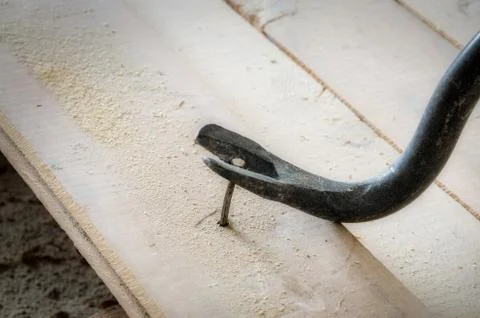 Nail puller pulls an old nail from the floorboard Stock Photos