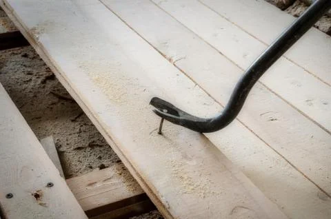 Nail puller pulls an old nail from the floorboard Stock Photos