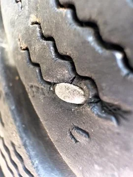 Nail puncturing car tire causing flat irreparable damage 库存照片
