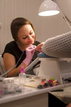 In the nail salon client, the tips of gloves handles the nails using the nail Stock Photos