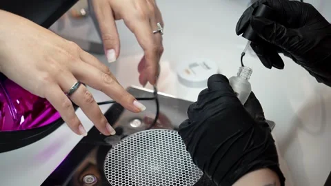 Nail technician applies the first base coat to a client's fingernail before Stock Footage 341929576