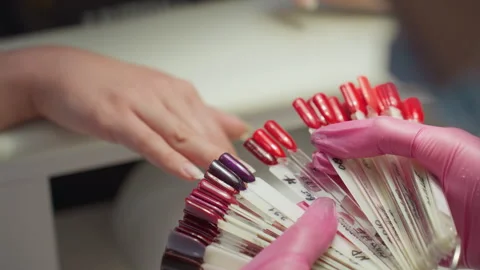 Nail Technician Comparing Multiple Nail Colors on Customer Finger Stock Footage 310264180