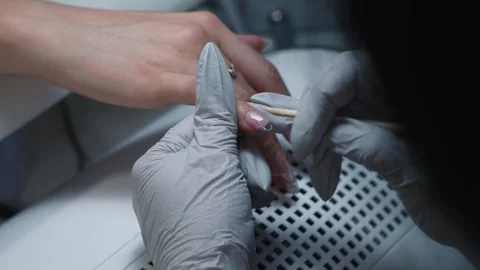 Nail technician evenly applies polygel with orange stick on nail Stock Footage 343801197