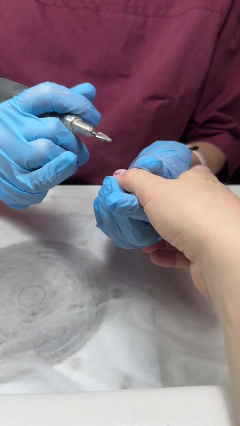 Nail technician in gloves removes old gel coat with e-filing, close-up view Stock Footage 329694722