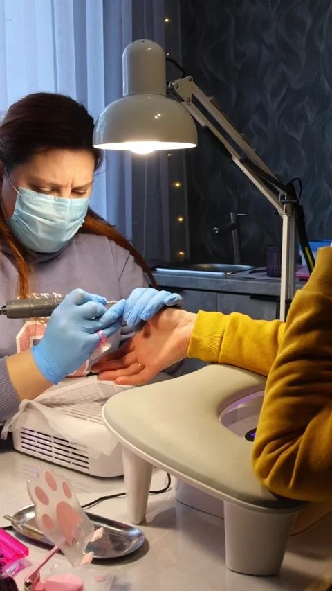 Nail technician in a mask doing hardware manicure for a client in a salon. .. Stock-Footage 343530148