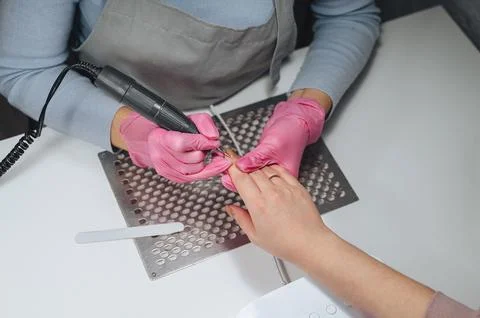 A nail technician performs a hardware manicure on a client Stock Photos