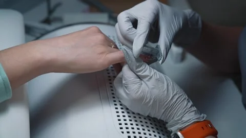 Nail technician shapes glitter pattern using magnet over gel polish Stock Footage 343802294