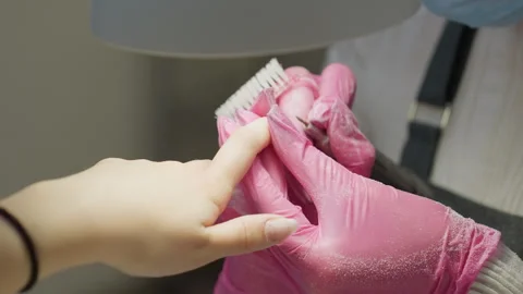 Nail technician using brush and filer on customer wearing black bracelet Stock Footage 310260789