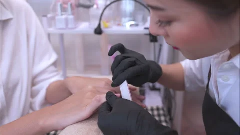 A nail technician is using nail file to polish nails of a customer Stock Footage 278605542