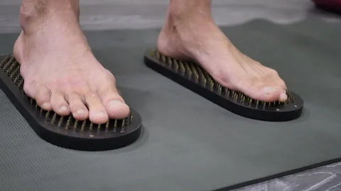 Nailing. Men's feet stand on the sharp nails of the Sadhu board. Indian Practice Stock Footage 223597789