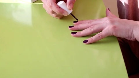 Nails, dark red nails, on green backgraound, white hands, manicure do yourself Stock Footage 73389421