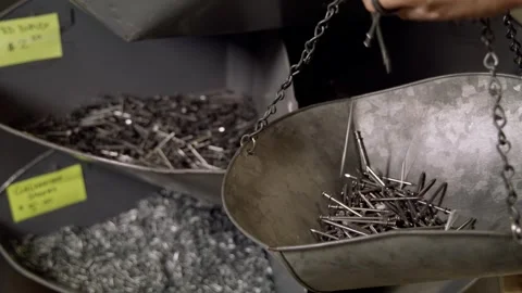 Nails falling into old metal scale with others in BG 5K Stock Footage 315699920