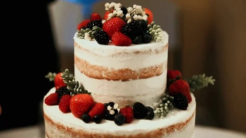 Naked cake, white, three-tier, wedding, someone decorates a fruit cake Stock Footage 101045315