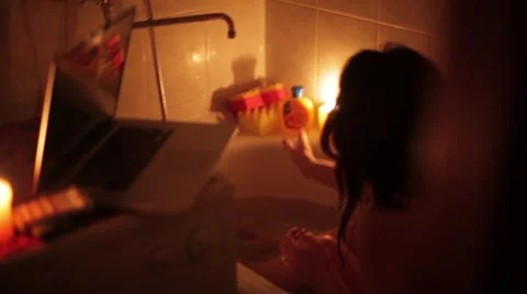 Naked girl sits in a bath and washes her hair,watching a movie on the laptop Video stock 59798380