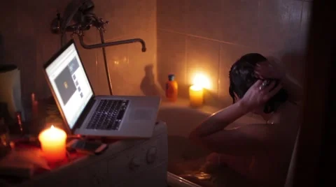 Naked girl sits in a bath and washes her hair,watching a movie on the laptop Video stock 59798615