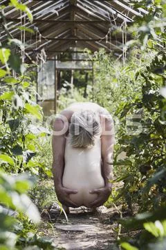 A naked man with his hands on the buttocks of a naked woman crouching in a Stock Photos
