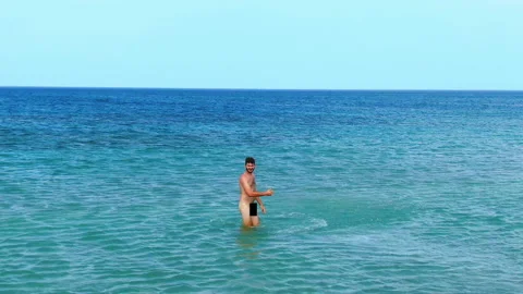 Naked man splashed water ocean on nudist beach. Nudity people playful enjoy sea. Stock Footage 151657664