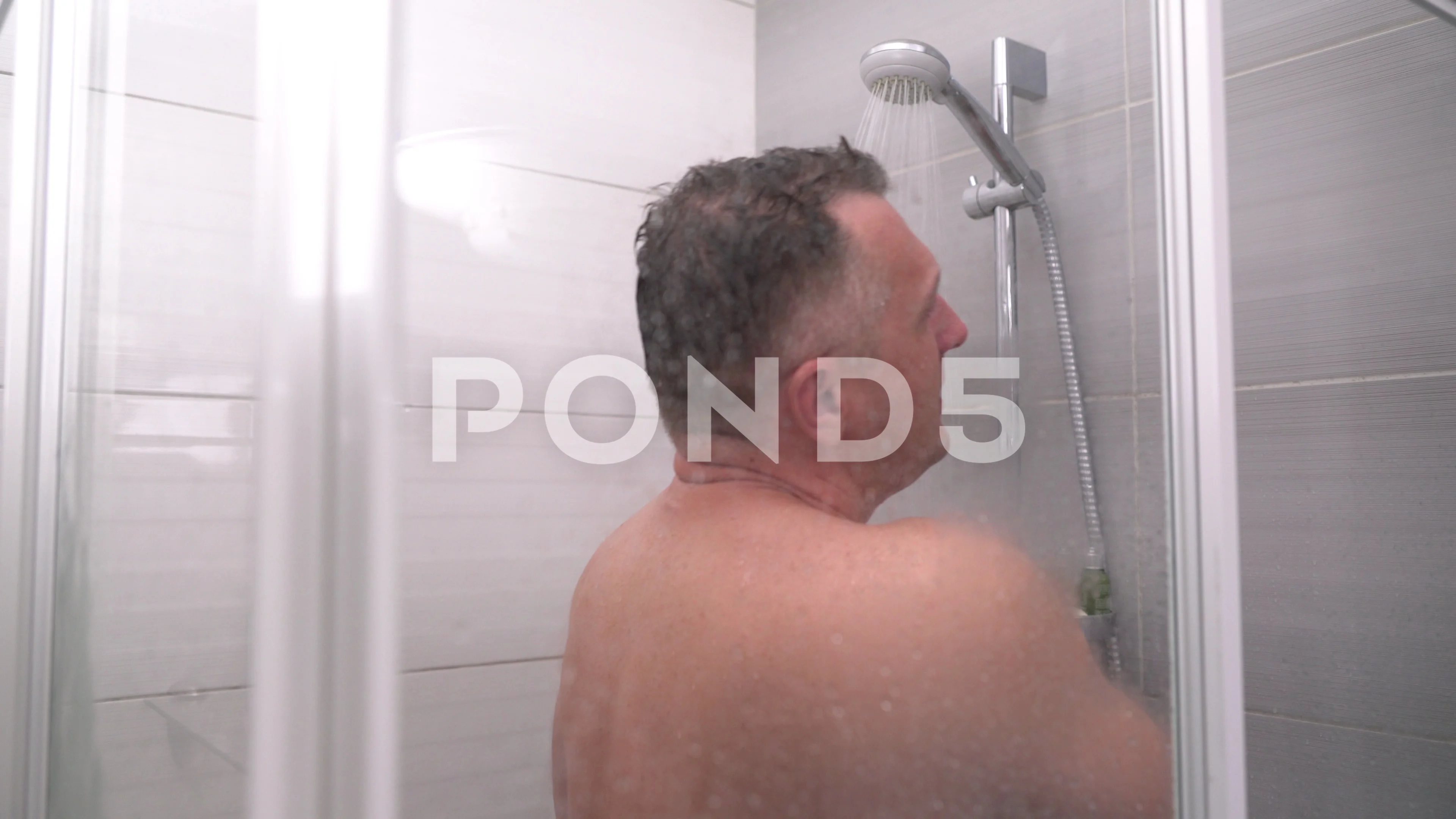 Naked middle-aged man taking a hot shower