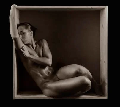 Naked muscular Mixed Race woman covering breasts in box, Stock