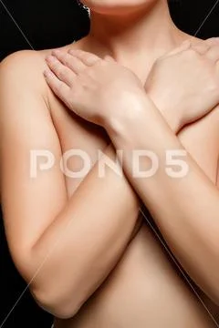 Topless young black woman with arms over breasts Stock Photo