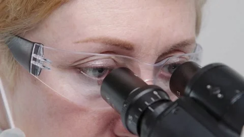 A nanotechnologist examines tiny microscopic structures under a microscope. Stock Footage 336583723