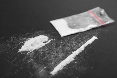 Narcotics on black table, plastic bag and white line. Stock Photos