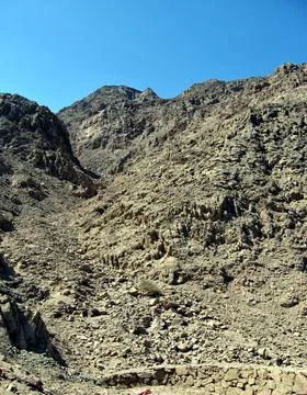 Narrow ascent to the mountain from a stone fence. Yellow and gray stones an.. Stock Photos