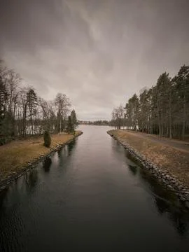 Narrow Banks Bordered By Pine And Birch Trees Under Heavy Clouds Фото