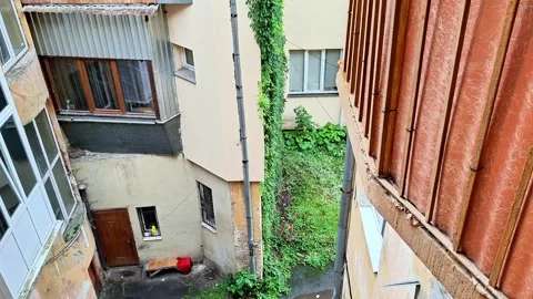 Narrow Courtyard Between Weathered Apartment Buildings with Ivy and rain Stock Footage 341656430