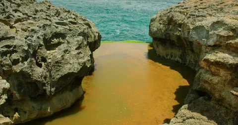 Narrow gap between two large jagged rocks filled with water leading to open Stock-Footage 326017583