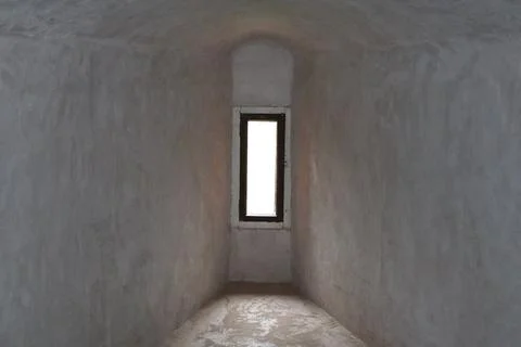 Narrow glazed window in the thick stone wall of the old castle Stock Photos