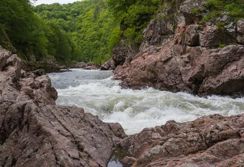 A narrow gorge through which a river flows, the sun's rays break through the Stock Photos