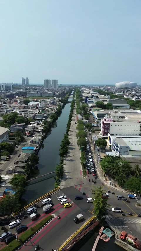 Narrow lake flanked by tree-lined roads and buildings 스톡 동영상 332364140
