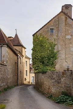 Narrow lane winding between old stone walls and village houses, Yonne, Mont.. Stock Photos