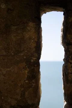 Narrow long vertical security window of the fortress overlooking the sea with Stock Photos