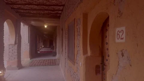 Narrow mud brick corridor with arched doors and lantern light in Morocco Stock Footage 335962961
