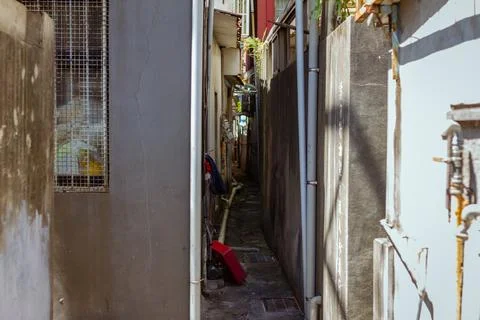 Narrow Passageway Between Old Weathered Buildings with Exposed Pipes and Sh.. Stock Photos