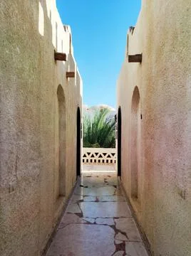 Narrow passageway between two African-style buildings against a blue sky. Foto stock