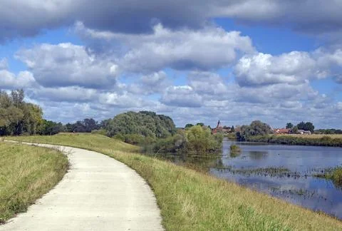 A narrow path along a river with a view of several houses and trees, Stock Photos