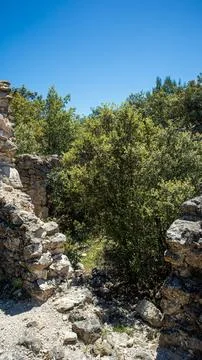 Narrow path through ancient stone ruins of a deserted village in wild Medit.. Fotos de archivo