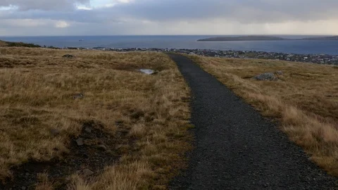 Narrow pathway between grass on top of a hill facing an open sea in background Stock Footage 92639389