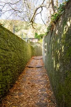 Narrow pathway through mossy stone walls Stock Photos