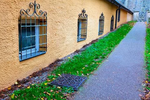 Narrow paved path alongside a yellow building in autumn Stock Photos