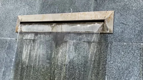 Narrow but powerful water stream goes out of the wall slit and falls down Stock Footage 260614577