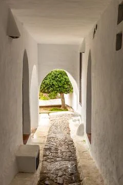 A narrow stone path between the white walls of the building Stock Photos