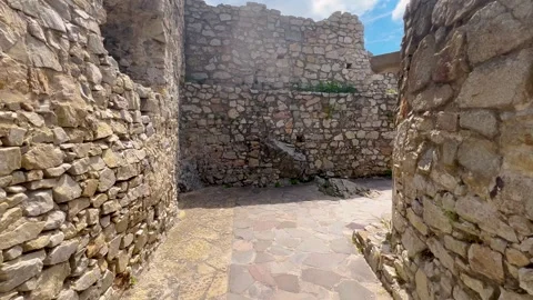 A narrow stone pathway surrounded by ancient, weathered walls Video stock 297761397