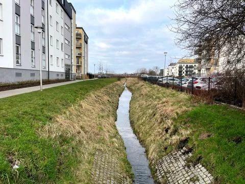 A narrow stream flows between city houses in the spring Stock Photos