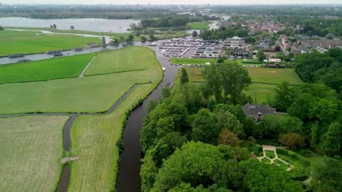 A narrow water channel winds through a green forest, reflecting the surrounding Stockbeeldmateriaal 312575366