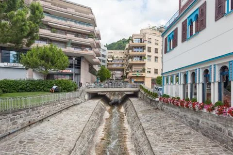 Narrow water stream flowing down through stone paved riverbed built to protec Stock Photos